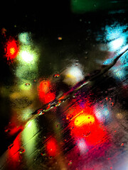 Abstract lights falling on a wet windshield at night