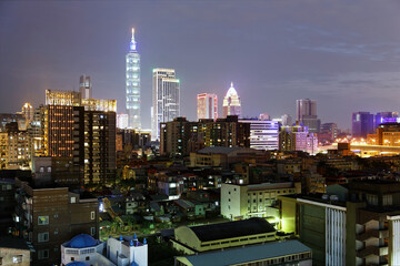 Fototapeta premium Night skyline of Downtown Taipei, vibrant capital city of Taiwan, with the famous landmark 101 Tower standing among high-rise buildings in Xinyi Financial District and city lights dazzling in the dark
