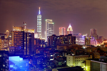 Night skyline of Downtown Taipei, vibrant capital city of Taiwan, with the famous landmark 101 Tower standing among high-rise buildings in Xinyi Financial District and city lights dazzling in the dark
