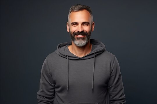 Handsome middle-aged man in black sweatshirt over dark background.