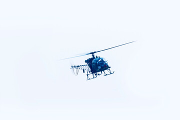 Combat helicopter is flying on isolated blue sky.