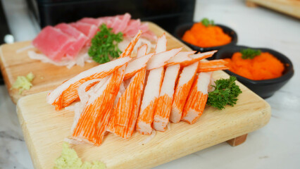 Sliced Imitation crab stick with wasabi serve on wooden dish. Japanese food crab sticks or surimi and wasabi prepared for eating on table, traditional Japanese food.