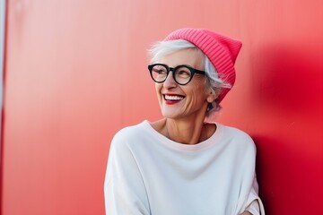 Portrait of happy senior woman in eyeglasses against red wall