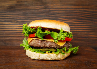 Burger, sandwich, hamburger with meat cutlet, tomato, cucumber and cheese on a wooden background