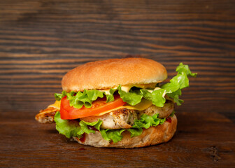 Burger, sandwich, hamburger with chicken breast, tomato and cheese on a wooden background