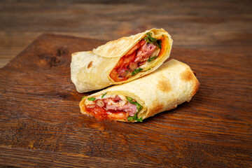 Shawarma, doner with beef, cabbage and tomato on wooden background