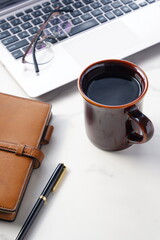 コーヒーを飲みながらノートパソコンでデスクワークをしているイメージ
