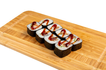 Japanese sushi roll in nori with eel and teriyaki sauce on a wooden board, isolated.