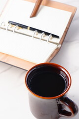 コーヒーを飲みながらシステム手帳を開いてデスクワークをするイメージ
