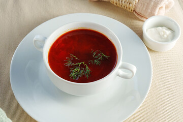 Presented bowl of creamy tomato bisque soup, adorned with a gleaming silver spoon.