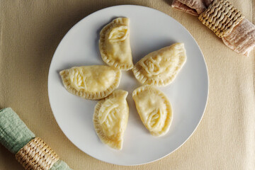 Elegance of perfectly crimped crescent dumplings, or ravioli, presented on a white plate, ready to entice any food connoisseur.