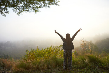 Rear view of woman standing in forest during misty morning