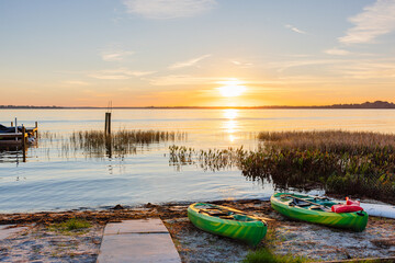 Serene lake sunrise with kayaks on beach ready for adventure