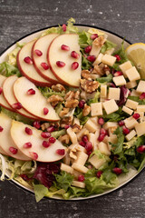 plate with apple, greens, walnuts, cheese, and pomegranate seeds