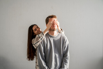 a young lovely couple covering each other's Eyes With Hands in a Playful Surprise Gesture Indoors