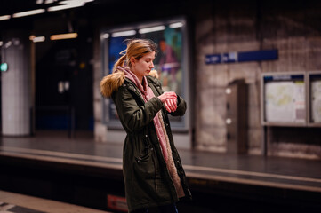 Checking Time in Subway Station, Pensive young woman checking her watch while waiting alone at a subway station