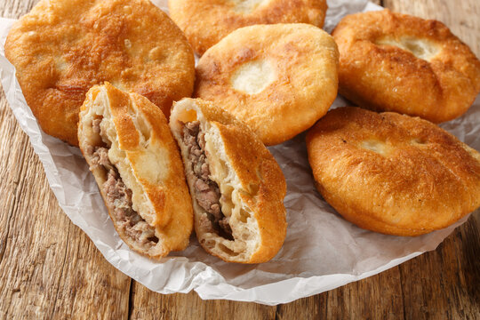 Popular food tatar cuisine peremech belyash pies with mee closeup on the paper on wooden table. Horizontal