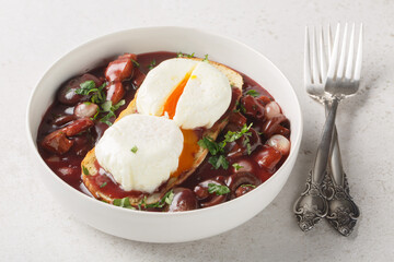 Oeufs en meurette is a traditional dish from Burgundian cuisine based on poached eggs and meurette sauce or bourguignon sauce closeup on the plate on the table. Horizontal