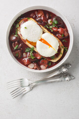 Eggs meurette or poached eggs with red wine sauce closeup on the plate on the table. Vertical top view from above