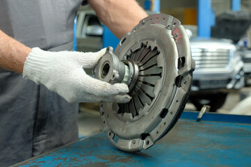 Car repair at a car service center. The clutch kit is new. An auto mechanic monitors the integrity of the drive disc, the driven disc and the exhaust bearing.