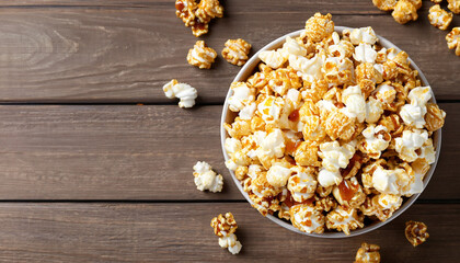 Obraz na płótnie Canvas popcorn with caramel in bowl on wooden background, top view
