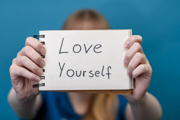 Kobieta trzyma kartkę z napisem kochaj siebie,  ważny przekaz