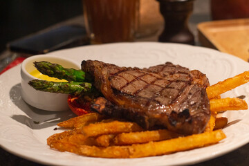 Top down view of barbecue fillet steak served with asparagus French fries and mustard sauce on plate