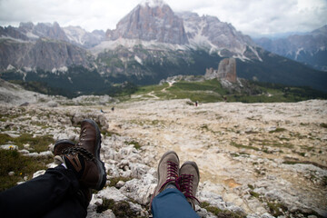 Trekking boots of a hiker couple while sitting on top of a mountain in Dolomites, Italy
