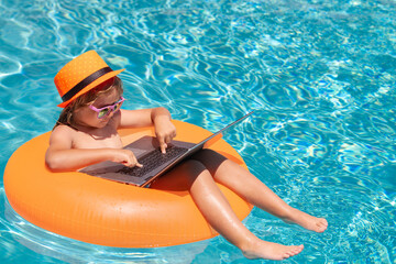 Summer business and online technology. Child sitting in swimming ring in pool and using laptop. Shopping online, freelance concept, summer travel.