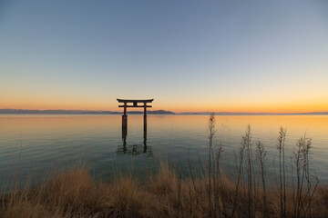 A large Torii gate on Lake Biwa in Japan located next to the Shirahige Shrine at sunset....