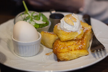 Small cube of french toast and boiled egg served with vegetable salad and syrup on a white ceramic plate, Kyoto, Japan