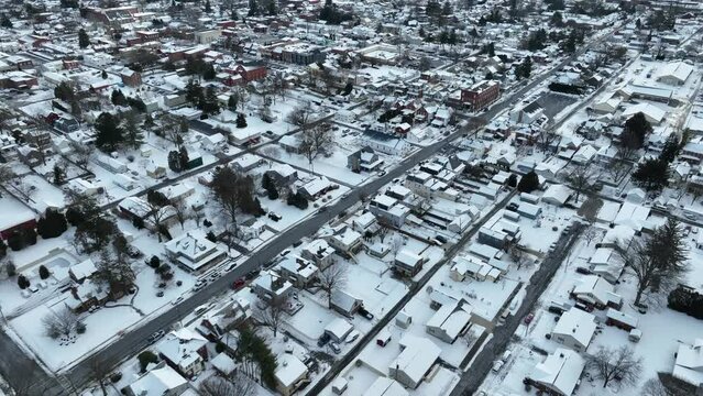 Aerial of white USA town covered in snow. City with urban houses and homes during holiday winter storm. Frame filled with residential town housing.