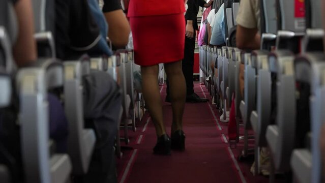 Medium view of air hostess or flight attendant in red suit holding opaque trash bag
