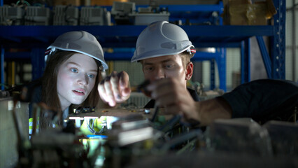 A young female engineer and a male supervisor work together in robotic arm spare parts warehouse,...