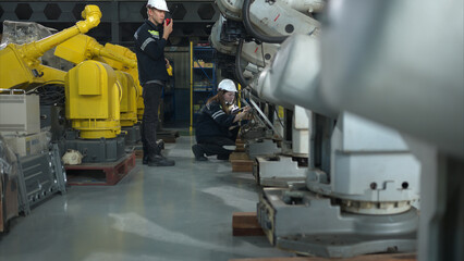 Both of engineers working together in a robotic arm factory, Robotic arm industry and engineering concept.