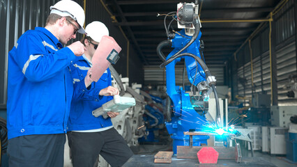 Industrial workers working with robotic arm welding machine in factory, Robotic arm welding...