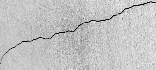 Big long curve diagonal ascending crack on old plastering wall. Copy space. Black and white photo....