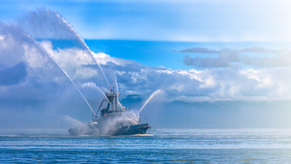 Fire hose boat spraying water on Kamchatka on Paciic ocean on sunlight