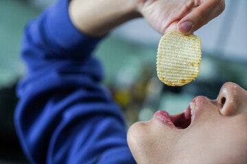 Woman using her hand to eat potato chips from a bowl, closed up shot.
