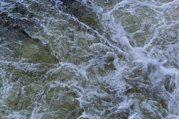 Close up detail of fierce white water river rapids from a clean deep green colored river forming a textured background