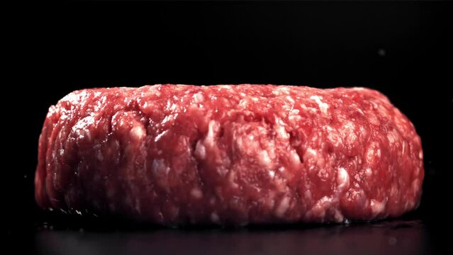 A fresh meat burger falls on a black table. Filmed on a high-speed camera at 1000 fps. High quality FullHD footage