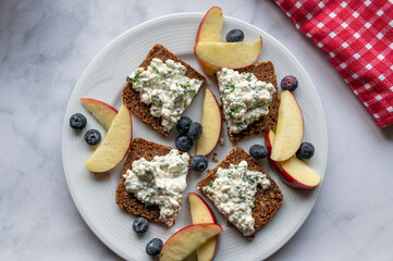 Healthy breakfast with whole grain bread with cottages cheese salad . Served with sliced apples and berries.
