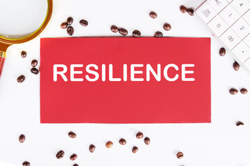 RESILIENCE writing on a red card on a white background with coffee beans and a magnifying glass