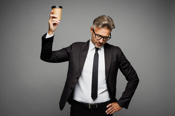 Naklejka premium Adult sad employee business man corporate lawyer he wear classic formal black suit shirt tie work in office hold takeaway delivery cup coffee to go isolated on plain grey background studio portrait.