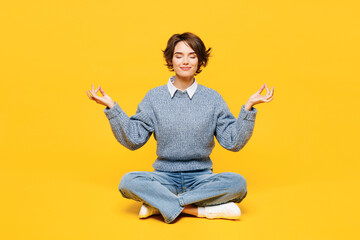 Full body young woman wears grey knitted sweater casual clothes sits hold spreading hands in yoga...