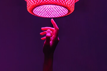 Hand of man under neon pink lighting against purple background