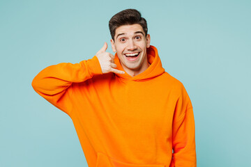 Young excited happy man he wearing orange hoody casual clothes doing phone gesture like says call...
