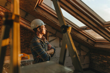 Architect wearing hardhat and looking out of window at construction site
