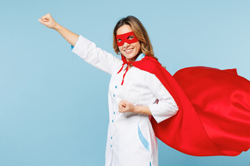 Side profile view female happy doctor man wear white medical gown suit red super hero coat mask work in hospital do fly gesture isolated on plain blue background studio. Healthcare medicine concept. © ViDi Studio