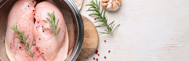Chicken breast raw with rosemary and red pepper on wooden background